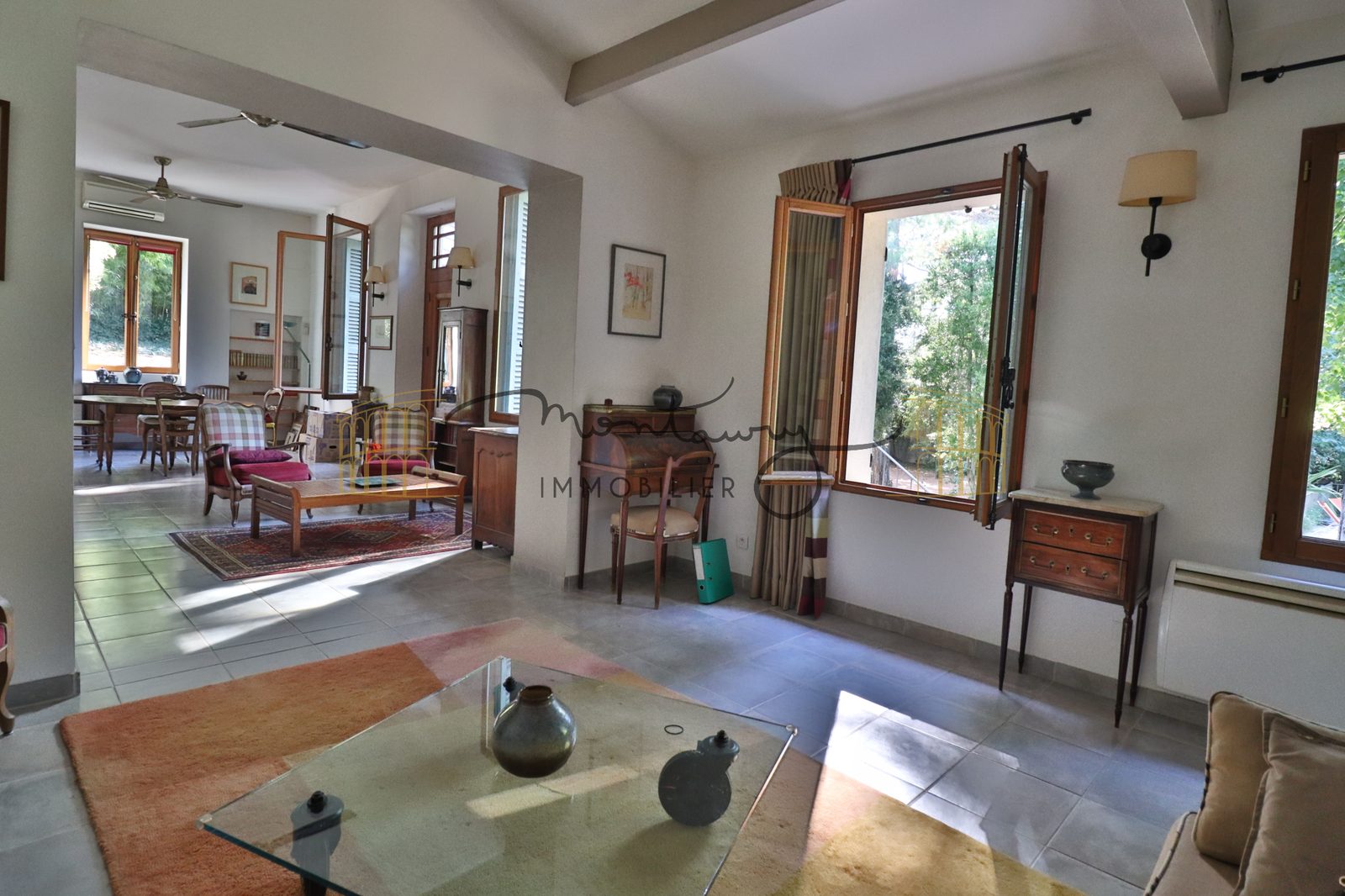 Salon avec table basse vitrée, grandes ouvertures et vue sur plusieurs pièces de vie en enfilade.
